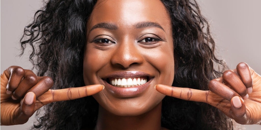 happy black woman pointing at her perfect white teeth picture id1187328108