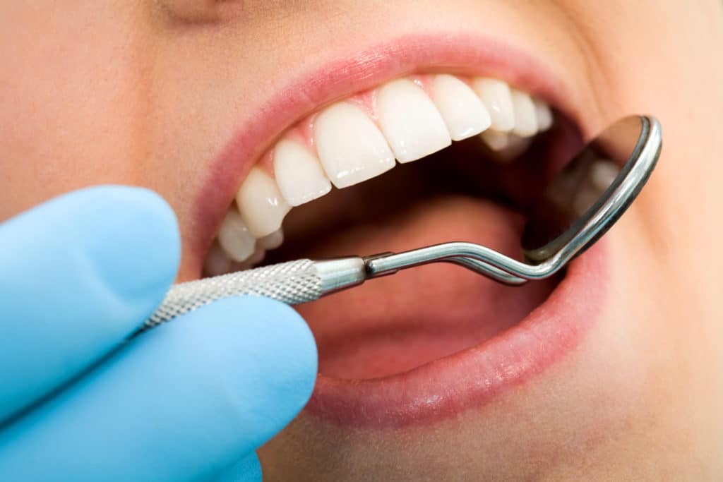 Close-up of female with open mouth during oral checkup at the dentist